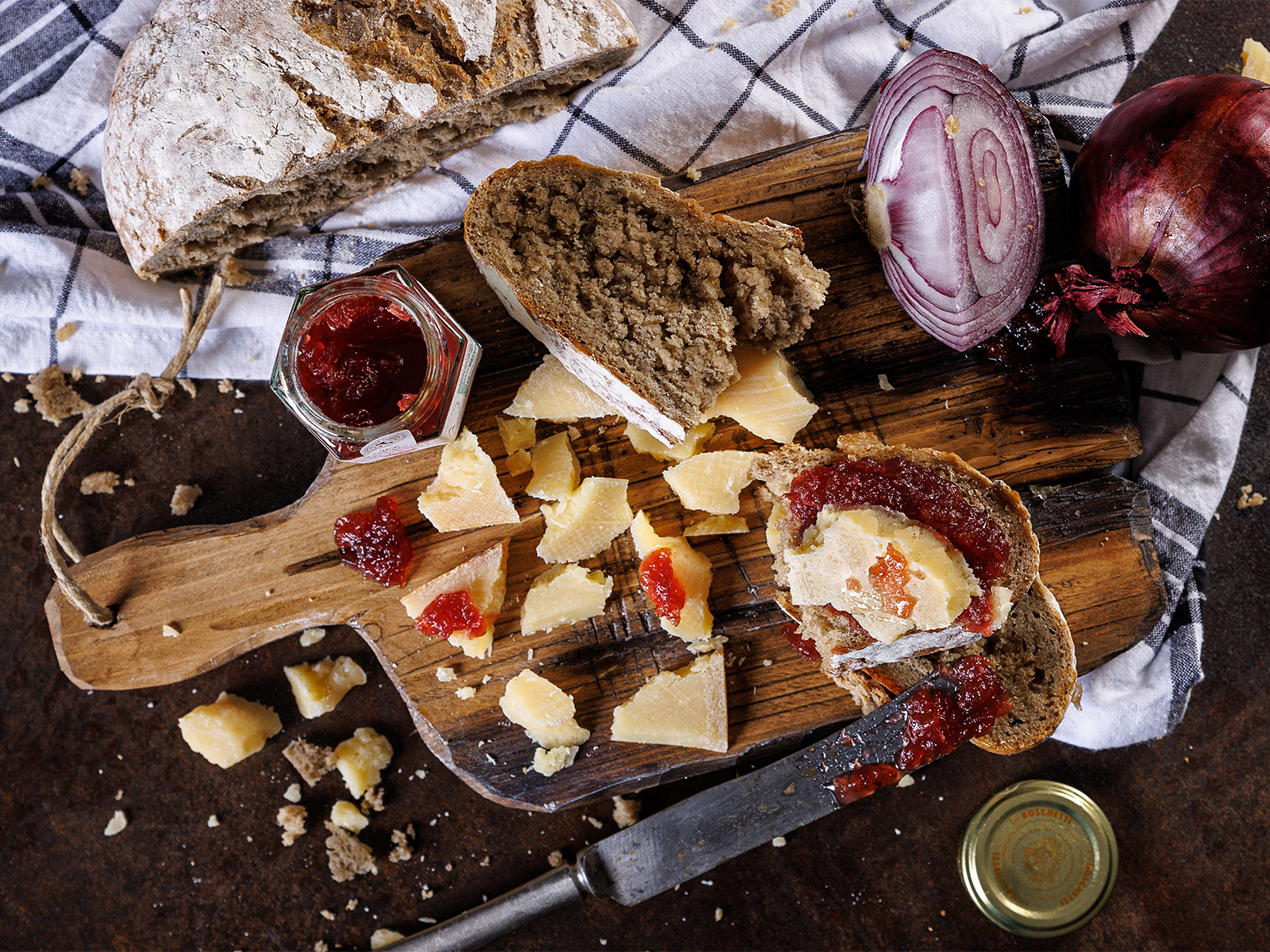 Tagliere con pane, marmellata, cipolle e parmigiano a tocchi