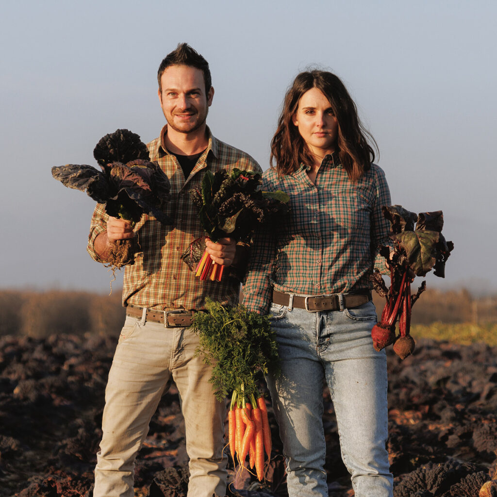 Due giovani contadini che sorreggono alcuni vegetali appena raccolti